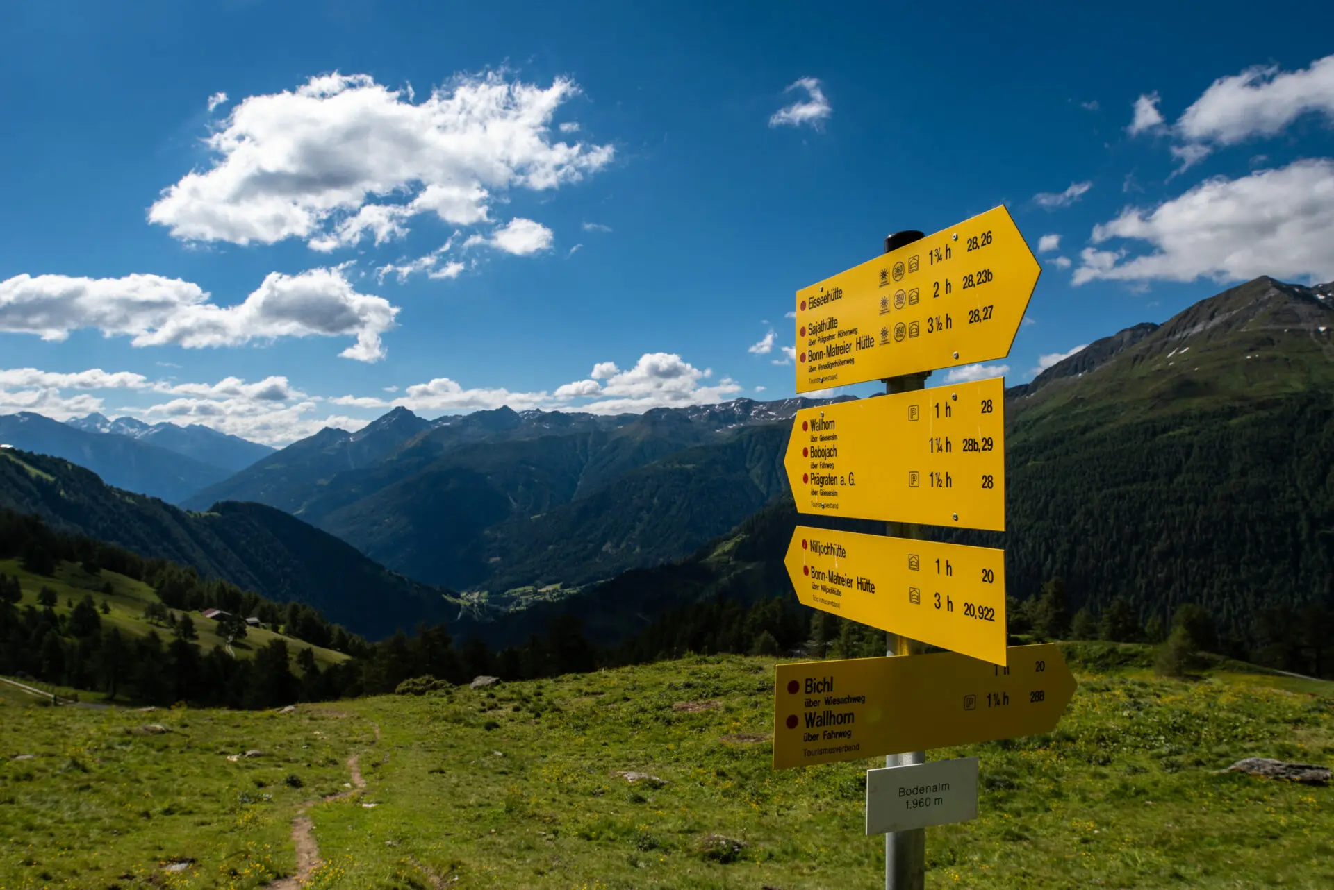 Ein gelber Wegweiser markiert verschiedene Wanderrouten in den Bergen